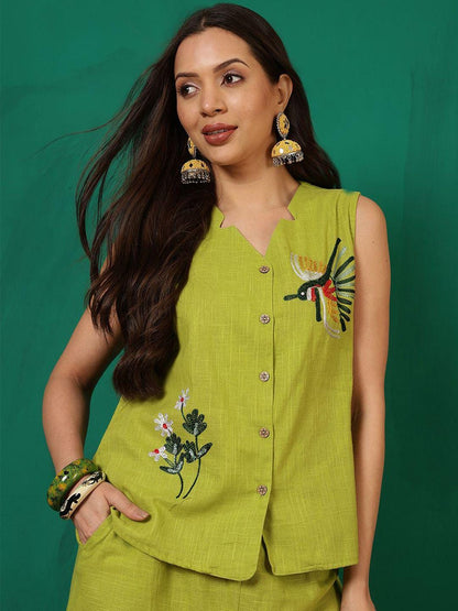 Puede incluir: Una blusa sin mangas de color verde lima con cuello en V y cierre de botones. La blusa presenta diseños bordados de flores y colibríes. La modelo lleva pendientes y pulseras doradas. El conjunto se combina con un pantalón corto a juego.