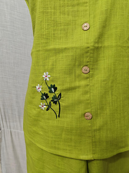 Puede incluir: Top sin mangas verde lima con botones de madera y diseño floral bordado en blanco y verde. La parte superior está hecha de una tela texturizada y parece ser parte de un conjunto.